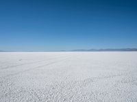 a lone snowmobile is moving across an open desert field with the mountains in the background