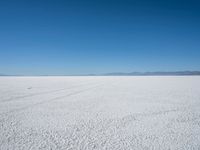 a lone snowmobile is moving across an open desert field with the mountains in the background