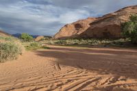 a desert area with sand and dirt with hills in the distance at dusk or at twilight