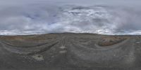 a spherical fish eye lens view of the desert landscape and clouds above it, with vegetation growing out of the mountains