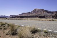 two lanes empty on an open road in the desert near mountains and a rocky cliff