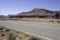 two lanes empty on an open road in the desert near mountains and a rocky cliff