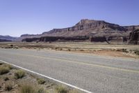 two lanes empty on an open road in the desert near mountains and a rocky cliff