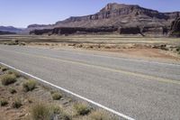 two lanes empty on an open road in the desert near mountains and a rocky cliff