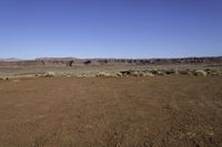 a view of the desert with horses in it, and mountains in the distance and a dirt road