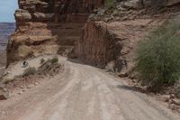 an old dirt road that is surrounded by some rocks and shrubs in the desert area