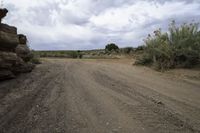 dirt road next to rocks on a cloudy day with grey sky in background on a hillside