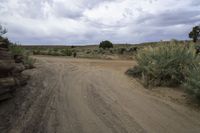 dirt road next to rocks on a cloudy day with grey sky in background on a hillside