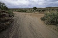 dirt road next to rocks on a cloudy day with grey sky in background on a hillside