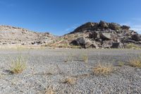 the rocks and dirt are in front of the desert landscape with some green grass growing