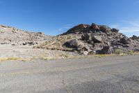 the rocks and dirt are in front of the desert landscape with some green grass growing