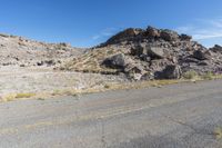 the rocks and dirt are in front of the desert landscape with some green grass growing