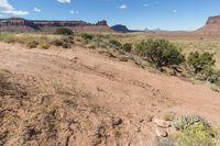 a very pretty view of some dirt mountains and trees in the background is blue and white clouds