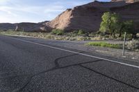 the side view of a road and dirt hill area in the desert with white lines