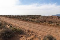 the desert landscape shows brown brush and shrubs in between blue skies and mountains in the distance