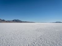 a view of a deserted desert with hills in the distance and a snow - covered ground