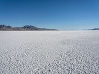 a view of a deserted desert with hills in the distance and a snow - covered ground