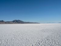 a view of a deserted desert with hills in the distance and a snow - covered ground