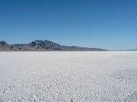 a view of a deserted desert with hills in the distance and a snow - covered ground