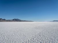 a view of a deserted desert with hills in the distance and a snow - covered ground