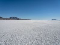 a view of a deserted desert with hills in the distance and a snow - covered ground