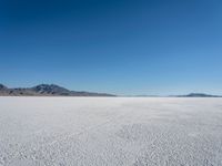 a view of a deserted desert with hills in the distance and a snow - covered ground