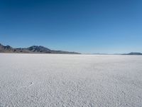 a view of a deserted desert with hills in the distance and a snow - covered ground