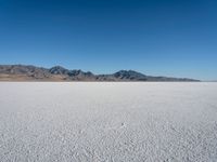 a view of a deserted desert with hills in the distance and a snow - covered ground