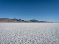 a view of a deserted desert with hills in the distance and a snow - covered ground