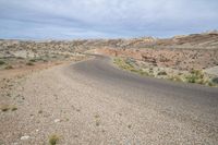 a dirt road in the middle of an arid desert area with sparse bushes and bushes