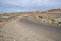 a dirt road in the middle of an arid desert area with sparse bushes and bushes