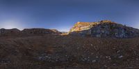 a full view of rocks in the desert near a river and hill top with some clouds in the sky