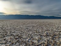 an empty landscape with lots of dirt in the foreground, and mountains on the right