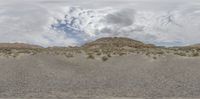 a person walks in the desert towards a mountain in the distance and a blue sky with some white clouds