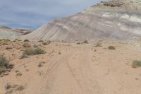 a dirt road leading through the middle of a desert plain, with mountains in the distance