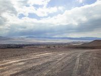 a dirt road with a truck on it, in the middle of the desert and a sky background