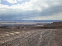 a dirt road with a truck on it, in the middle of the desert and a sky background