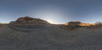 a skateboard ramp in a desert with mountains in the background and a road to the right