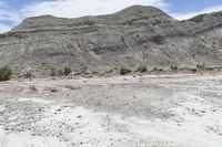 a white van is parked on the desert near some mountains and brushbrushes and trees