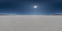 an empty desert is seen with several trees and mountains in the distance, with three bright circles over them