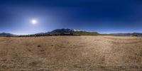 an abandoned building surrounded by desert land with mountains in the background, in an image done on circular 360, with lens - focused view