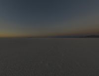 a lone person stands on the snow near the horizon, in the dark sky over some land