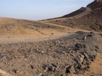 a truck on a dirt road in the desert with rocks and stones on the ground