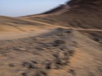 a truck on a dirt road in the desert with rocks and stones on the ground