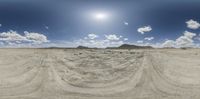 a desert has many tracks on the ground and blue sky with white clouds in it