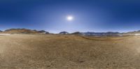 a panoramic view of the desert in front of a sunbursted sky