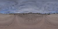 a panorama of a wide open desert field under stormy skies, including grey clouds and dark skies