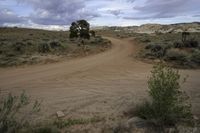 the dirt road is empty and the storm is coming in and the grass is very brown