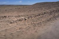 a car drives through a desert plain near an arid area and mountains in the distance