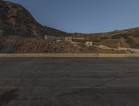 a lone motorcycle in the middle of the desert at dusk, with a building in the back ground